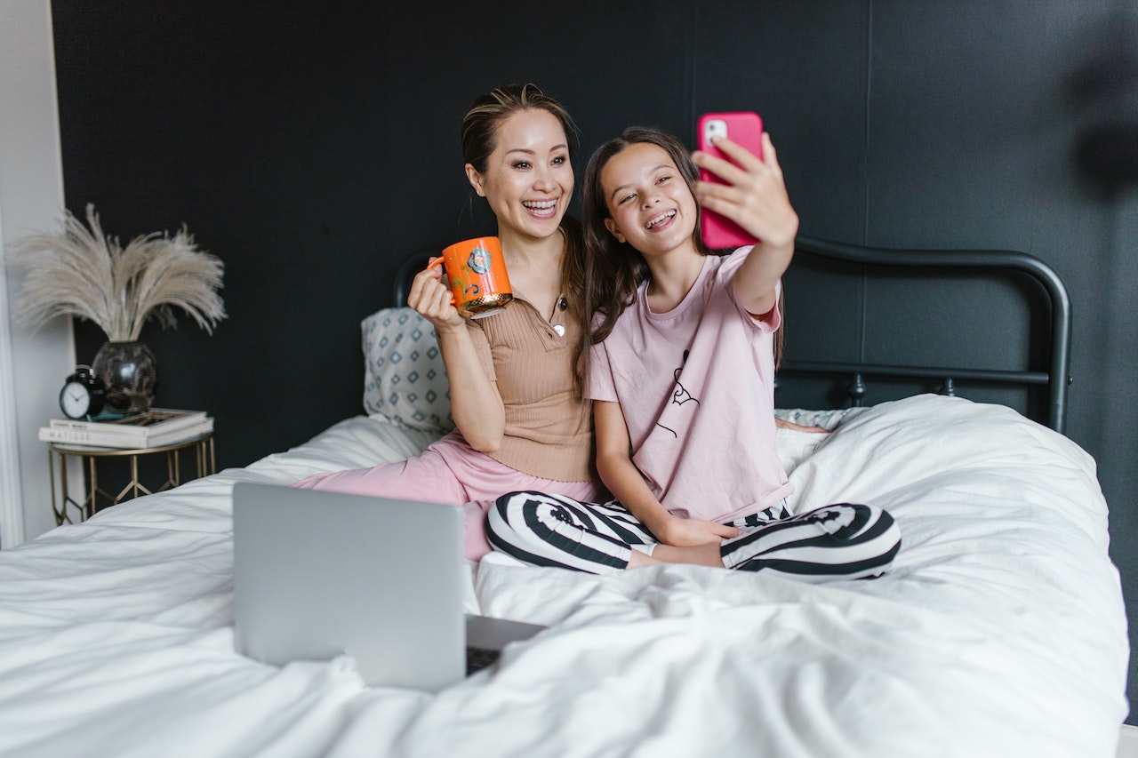 mama z córką na łóżku robią sobie selfie